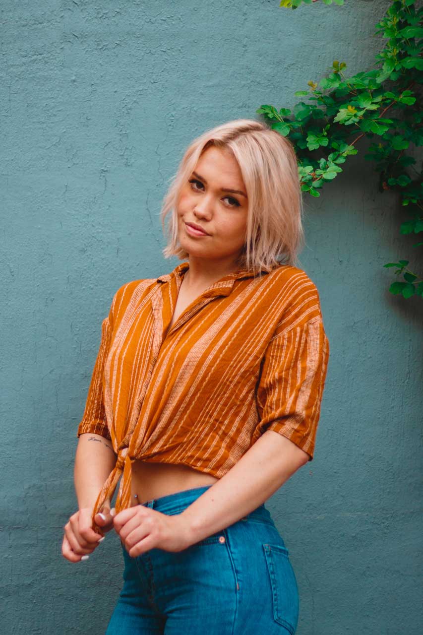 girl against blue wall wearing orange