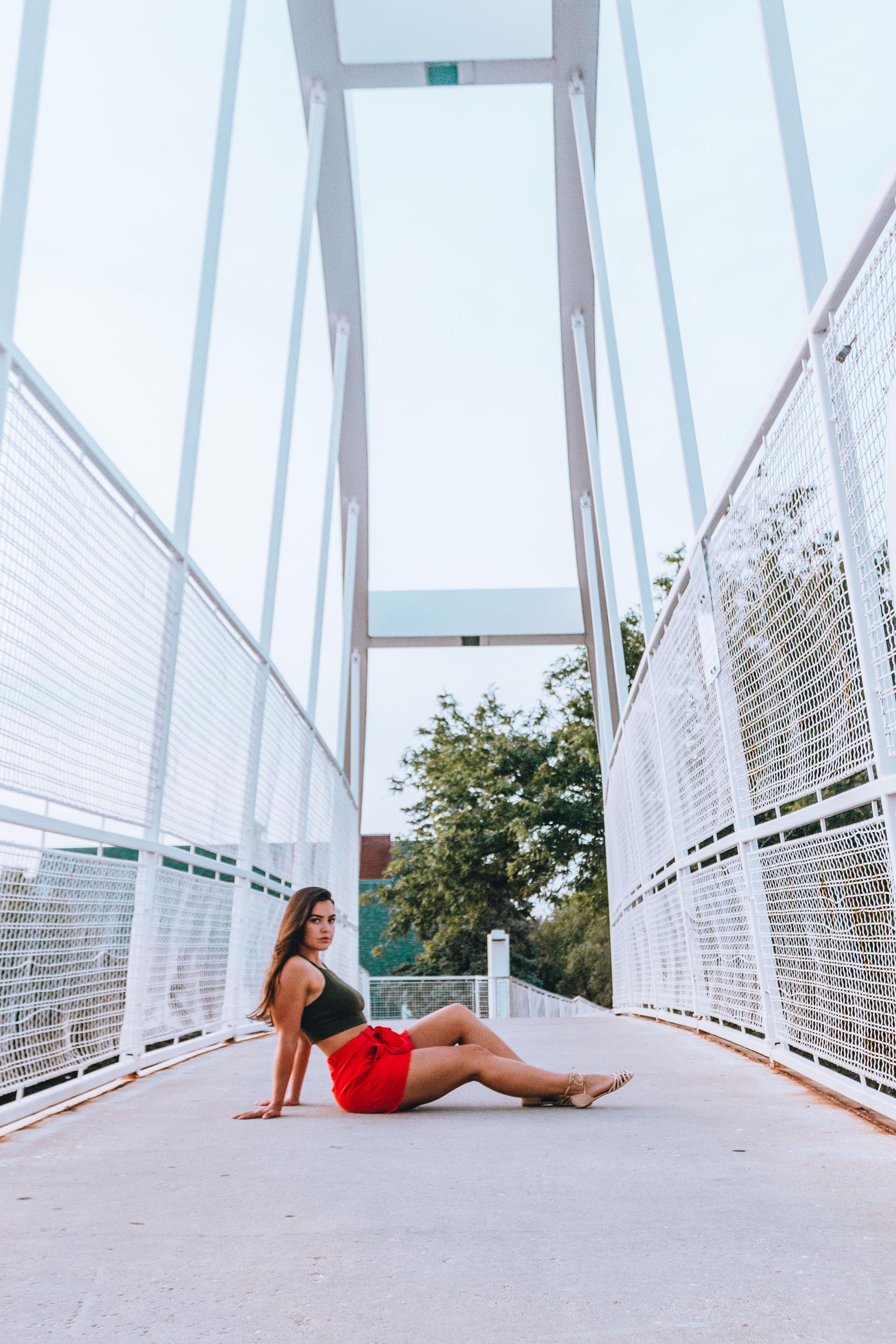 Girl sits down in the middle of a crossing bridge